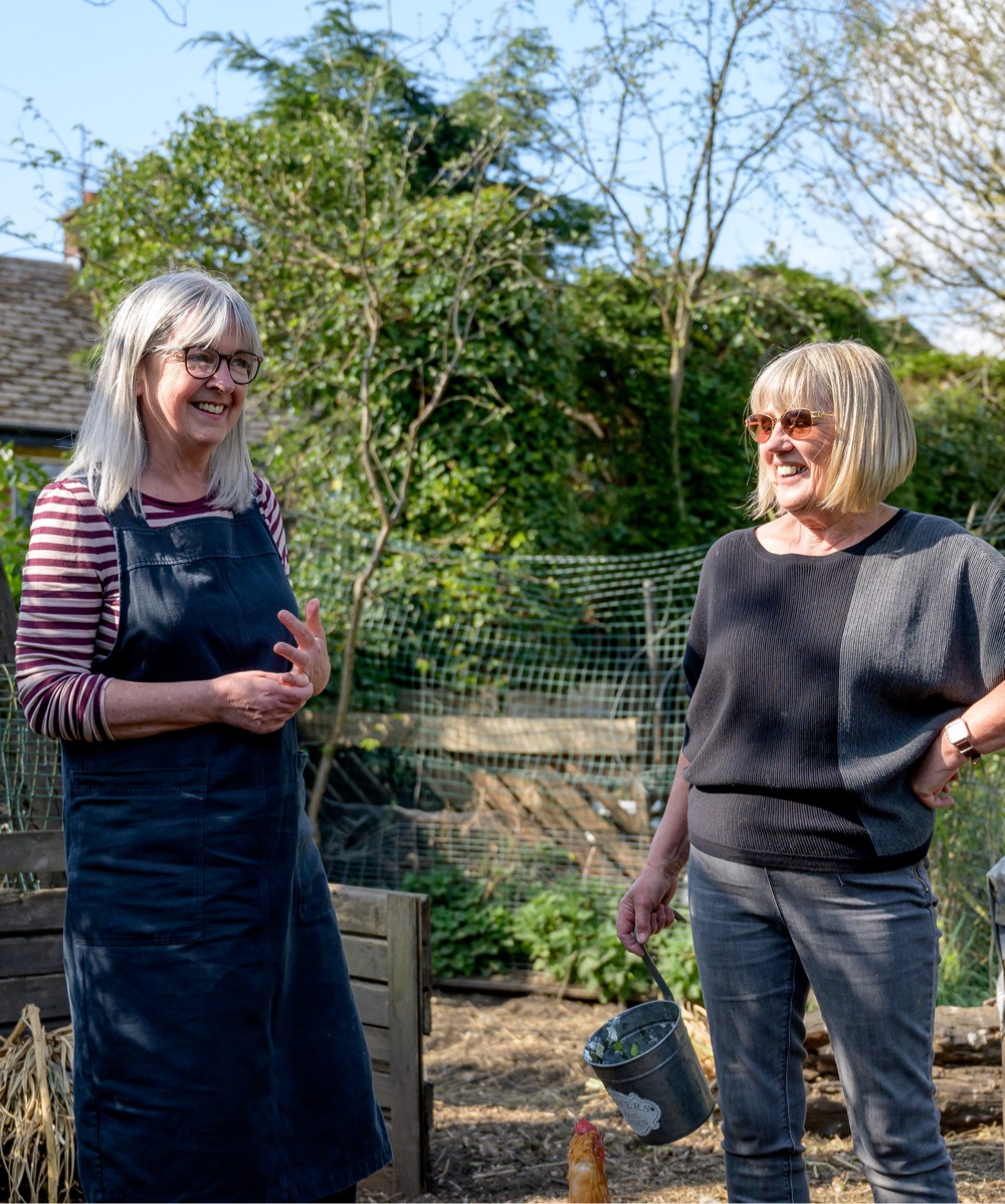 two middle aged white women laughing together in the garden